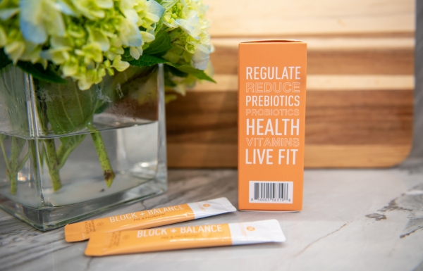 Lifestyle shot of NeoraFit™ Block + Balance Pre & Probiotic Powder on a table outside.